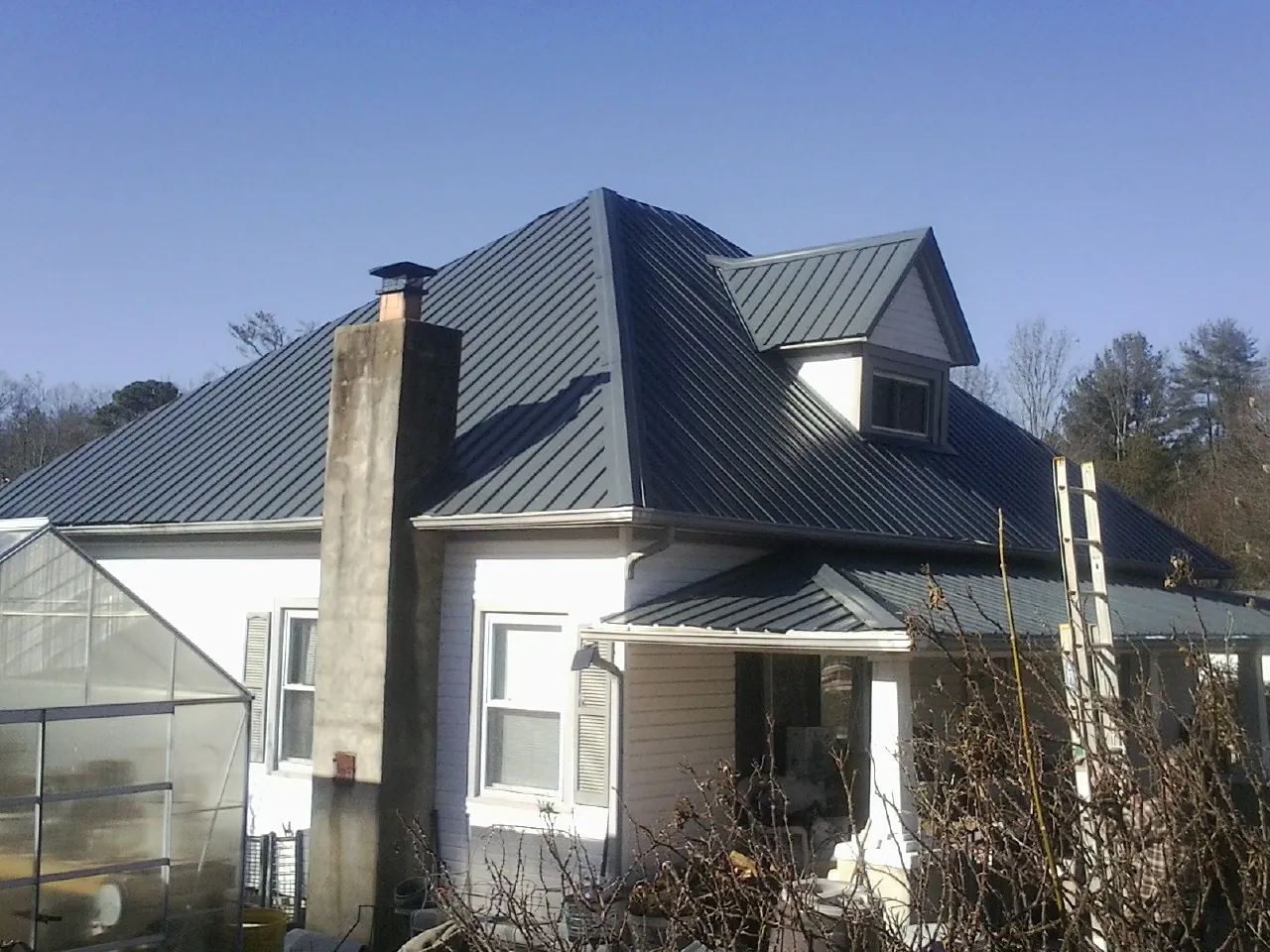 Dark blue standing seam metal roof on a white farmhouse with dormer — Slate & Tile Roof Repair by Roofing Brothers in Wetumpka