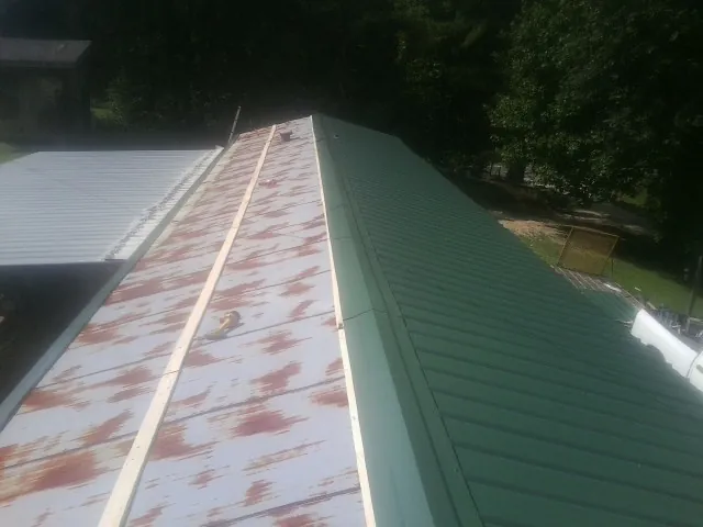 Old rusted panels beside newly installed green metal roofing — Wind Damage Roof Repair by Roofing Brothers in Wetumpka