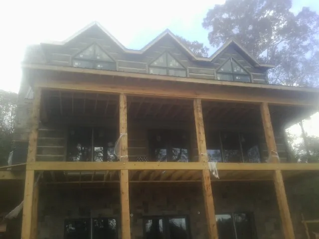 Dormers and porch framing on a large log home under construction — Roof Coating work by our crew in Wetumpka