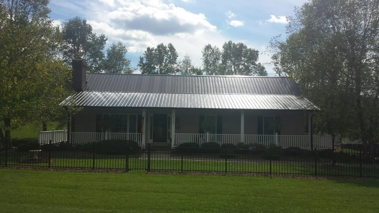 Gray metal roof on a brick ranch with a full width front porch — Gutter Guard Installation work by our crew in Wetumpka