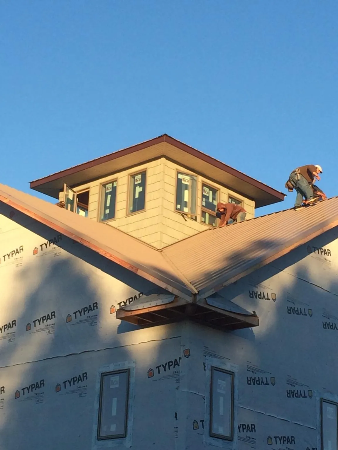 Roofers working around a rooftop cupola on a new metal roof at sunset — Roof Waterproofing in Wetumpka by Roofing Brothers